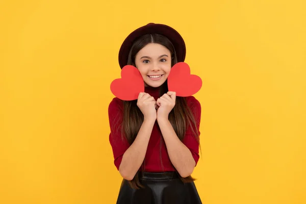 Gelukkig schattig kind met rood hart op gele achtergrond, liefde — Stockfoto