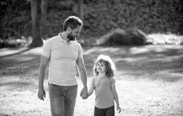 Anne ve babası küçük çocuğa çimlerde yol gösteriyor. Baba ve çocuk yaz günü.