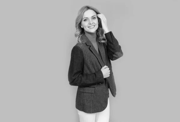 Весела блондинка в діловому казуальному британському піджаку на сірому фоні, краса — стокове фото