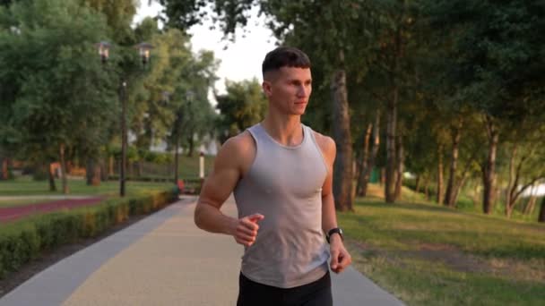 Athletischer Mann mit muskulösem Körper, der abends im Freien gegen Sonnenuntergang läuft, Motivation — Stockvideo