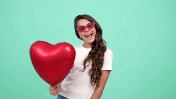 Portræt af glad barn i briller, der viser tungen hold hjerte fest ballon, fest sjov – Stock-video