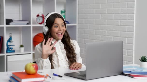 Bambino felice in cuffia studiare a scuola lezione online con il computer che dice ciao, videochiamata — Video Stock