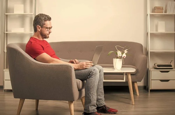 Serious guy in red tshirt and glasses work on pc in chair, psychologist — Stock Photo, Image