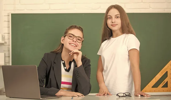 Professor sorridente em óculos com criança aveia lição com computador, de volta à escola — Fotografia de Stock