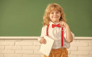 Kitapla gülümseyen çocuk. Sınıftaki genç çocuk. Okula dönüyorum. bilgi günü.