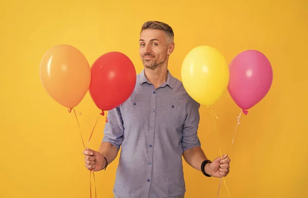 Smiling handsome man hold balloons on yellow background, holiday — Stock Photo, Image