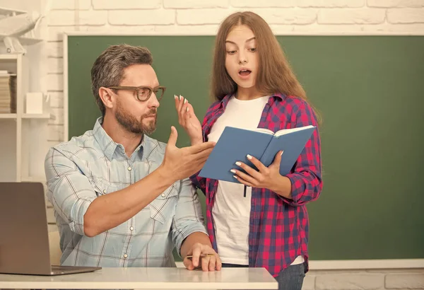 Verbaasd tiener meisje en leraar man op de middelbare school met werkboek op schoolbord, onderwijs — Stockfoto