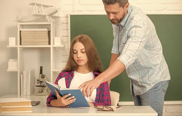 Dítě a táta sedí ve třídě s učebnicí na tabuli, škola — Stock fotografie