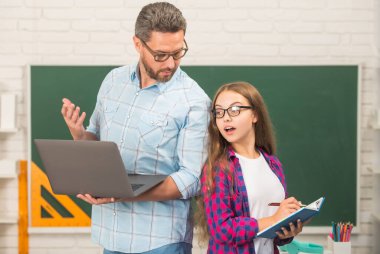 Özel öğretmen ve çocuk defterini tutuyor. Aile yardımı. Baba ve kızı defter kullanıyor..