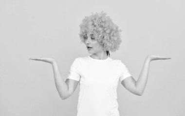 Süslü görünüşlü, turuncu peruklu, etkileyici komik kız. Ürün sunuyor, kopya alanı, seçim..