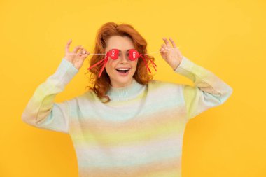 happy funny redhead girl with red heart sticks on yellow background. february 14