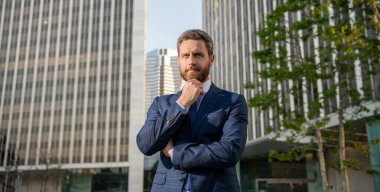 serious charismatic mature businessman in suit outside the office, business fashion