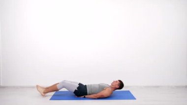 muscular guy doing abs exercise on fitness mat, pumping muscles