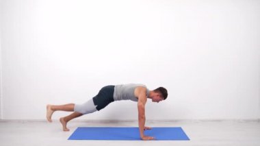 muscular man doing plank exercise for core muscles with leg up on fitness mat, sport