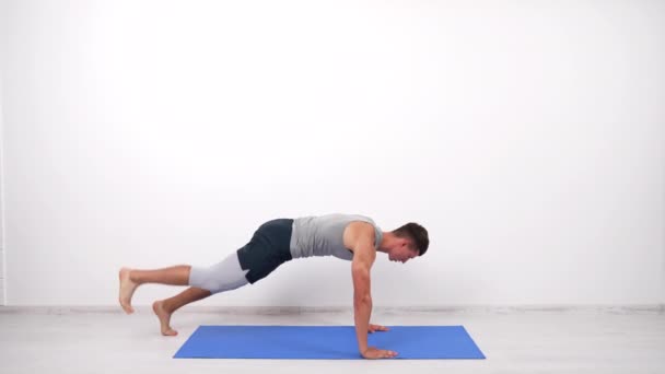 М'язистий чоловік робить дошку вправи для основних м'язів з ногою вгору на фітнес-мате, спорт — стокове відео