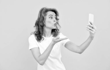 Kız kameraya el öpme hareketi yapıyor telefon sarısı arka plan, mobil cihaz