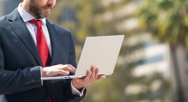 confident man in elegant suit typing on pc outside, copy space, networking