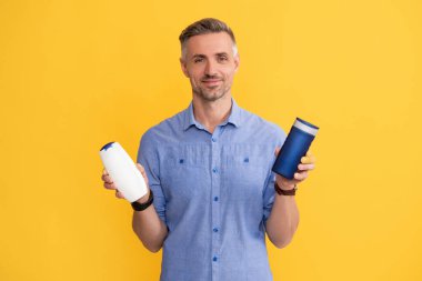 Adam şampuan şişesini ya da saç kremini seçiyor. Günlük alışkanlıklar ve kişisel bakım.