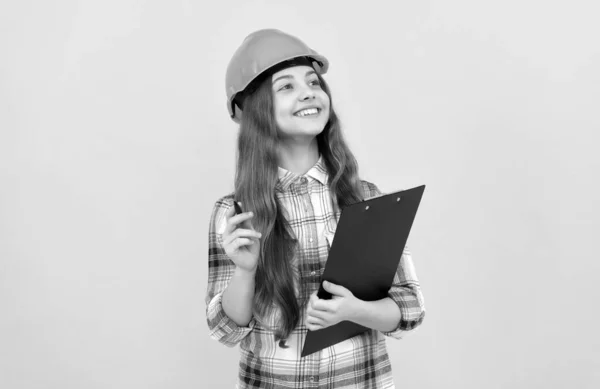 Heureux adolescent fille dans casque et à carreaux chemise prendre des notes sur presse-papiers, inspecteur — Photo