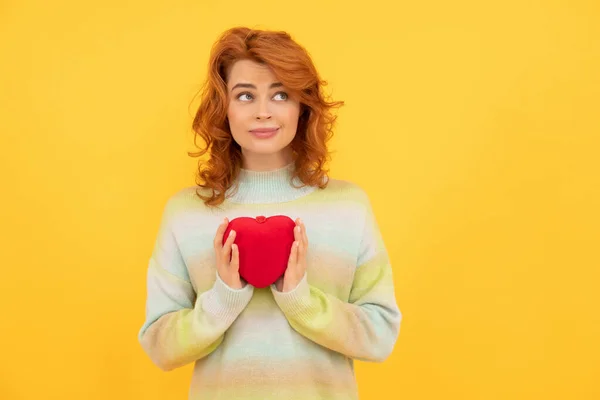Positive thinking redhead woman with red heart on yellow background. donation — ストック写真