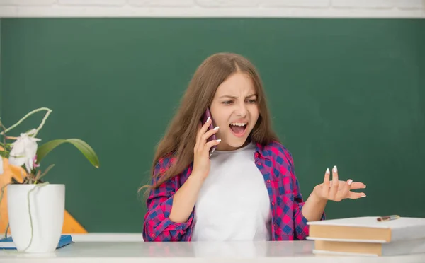 Aggressive kid speaking on smartphone in classroom at blackboard, phone call — Photo
