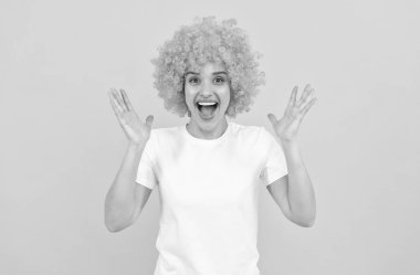 Sarı arka planda turuncu peruk takan çok mutlu, komik bir kız. Mutluluk.