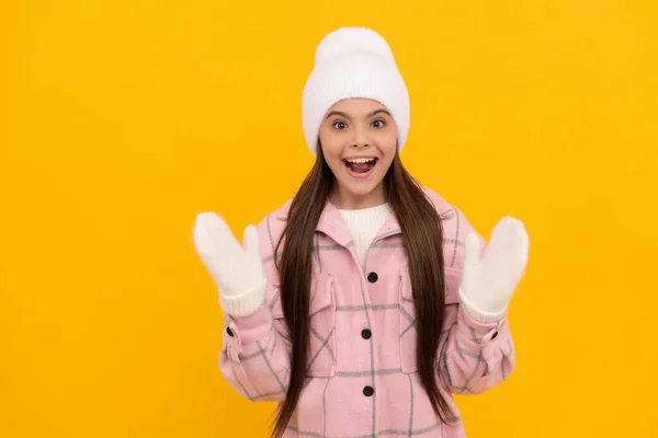 Niño sorprendido en manoplas de invierno y sombrero sobre fondo amarillo con espacio para copiar, la infancia —  Fotos de Stock