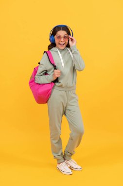 amazed child in headphones carry backpack. back to school. knowledge and education.
