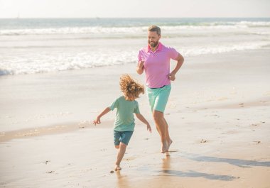 father and son running on morning beach. family travel weekend and vacation.