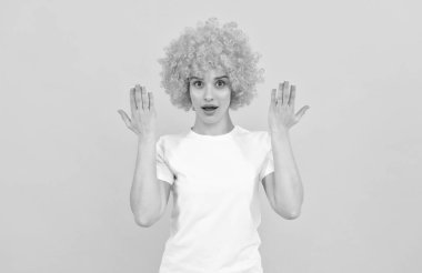 Kıvırcık palyaço peruklu, elleri havada, şaşırmış ucube kadın.