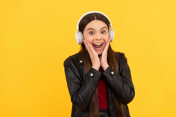 Amazed child in headphones on yellow background, music — Photo