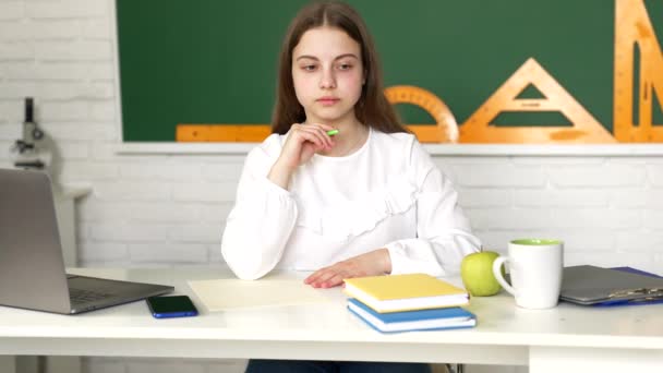 Στοχαστική κοπέλα γράφει σε βιβλίο αντιγράφων κάνει σχολική εργασία στο μάθημα, σχολείο — Αρχείο Βίντεο