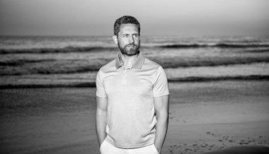 Gün batımında deniz üzerinde sakallı karizmatik bir adam. Sabah kumsalındaki traşsız adam..