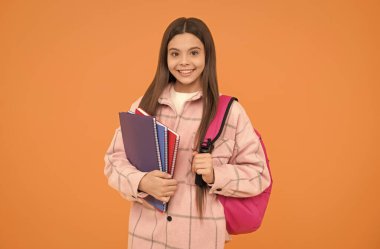 Sınıfa dönün. Neşeli öğrenci defterleri ve kitapları tutuyor. Okula dönüyorum. Tişörtlü genç kız.