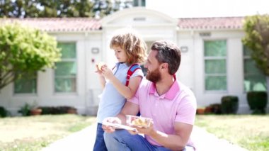 glad father and son eating food after school, slow motion, childhood