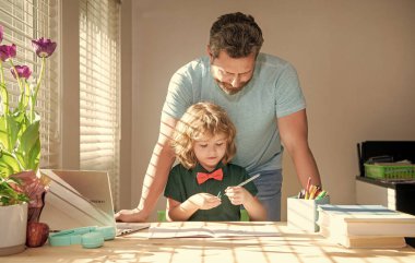 Ebeveynlik. Evde yazmakla meşgul baba ve oğul. Aile günü. Çocuk öğretmenle ders çalışıyor..