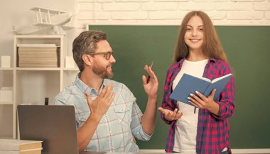 Baba ve çocuk eğitimi, karatahta geçmişi ve internet eğitimi hakkında kitap ve dizüstü bilgisayarla okulda..