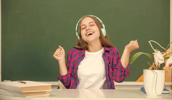 幸せなティーン女の子ホールド現代のヘッドフォンで高校で黒板,小児期 — ストック写真
