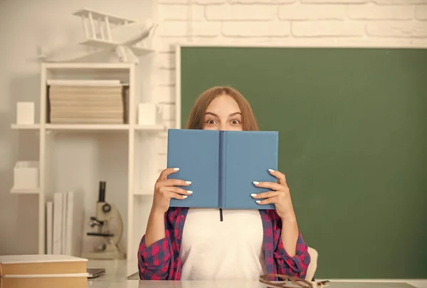 Дівчина-підліток у старшій школі позаду робочої книги на дошці, ерудиція — стокове фото