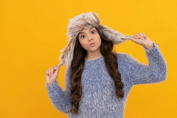 Grappig kind in trui en oorflap hoed op gele achtergrond, winter — Stockfoto