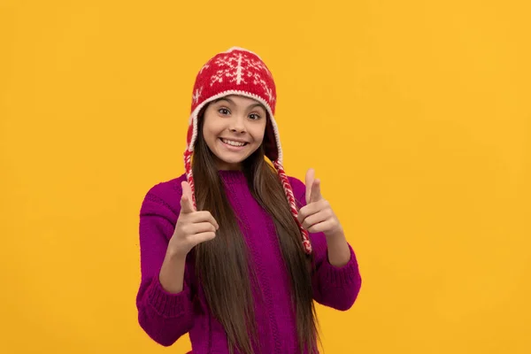 Sorridente ragazza adolescente indossare cappello a maglia dito puntato, tenere al caldo — Foto Stock