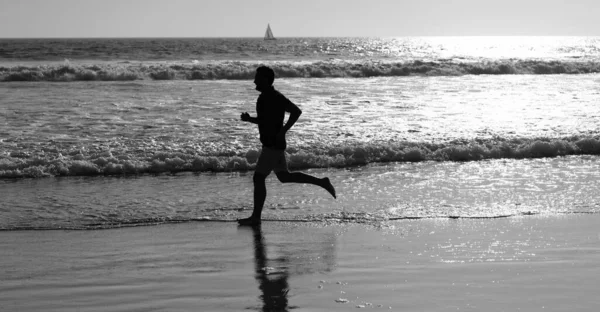 Wysportowany człowiek biegacz sylwetka biegać na letniej plaży z wodą morską i słońcem, sport — Zdjęcie stockowe