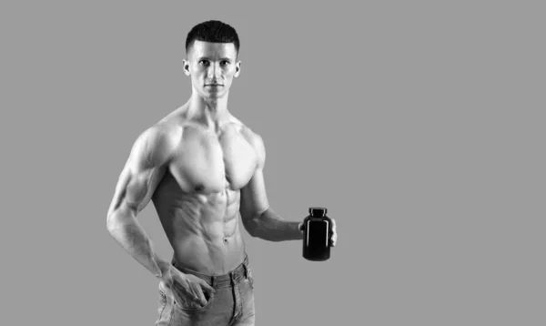 Guadagna massa. Il tipo muscoloso tiene una bottiglia di supplementi dietetici. Integratori alimentari sportivi — Foto Stock