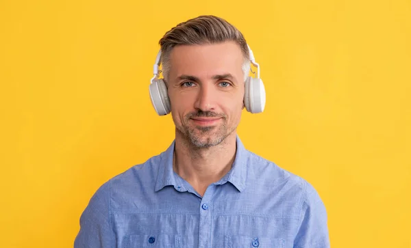 Улыбающийся человек слушать музыку в наушниках на желтом фоне, технологии — стоковое фото