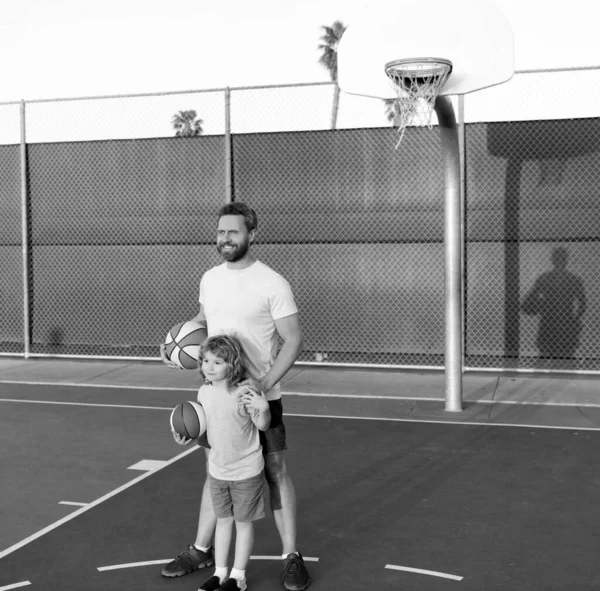Niño mantenga la pelota deportiva. infancia y paternidad. joven jugador con entrenador. pasar tiempo juntos. — Foto de Stock