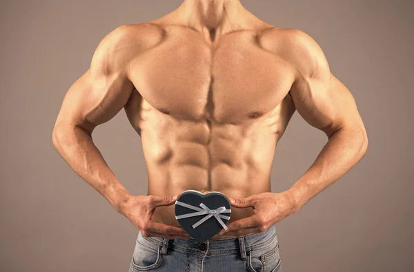Muscular man with fit six pack abs torso cropped view hold heart-shaped gift box, valentines day — Stock Photo, Image