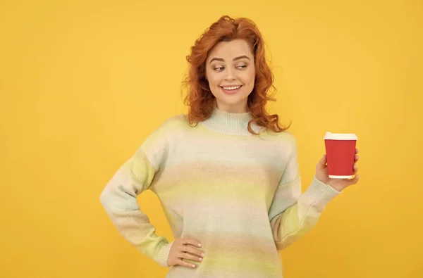 快乐的红头发女人喝着黄色背景的杯子里的外卖咖啡，早上的咖啡 — 图库照片
