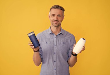 Adam şampuan şişesini ya da saç kremini seçiyor. Günlük alışkanlıklar ve kişisel bakım.