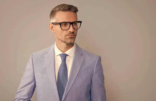 Зрелый бизнесмен в элегантной куртке и очках на сером фоне, копировальное пространство, формальная одежда — стоковое фото