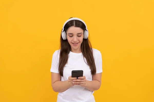 Glad dam i vit skjorta lyssna musik i hörlurar och chatta på telefon, musik — Stockfoto